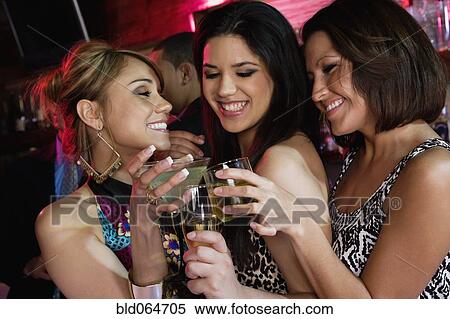 Stock Photography - Group of women drinking cocktails nightclub. Fotosearch