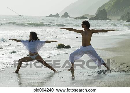 Stock Image - Hispanic couple doing yoga at beach. Fotosearch