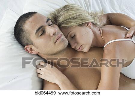 Stock Photo - Hispanic couple sleeping in bed. Fotosearch
