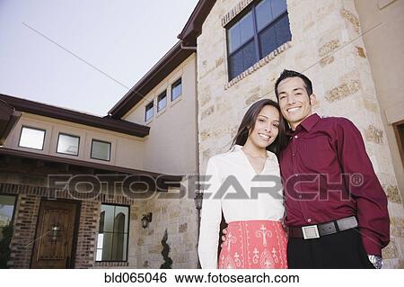 Stock Photograph - Hispanic couple standing outside house. Fotosearch