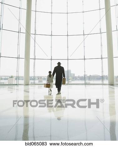 Stock Image - Hispanic father and daughter walking in airport. Fotosearch