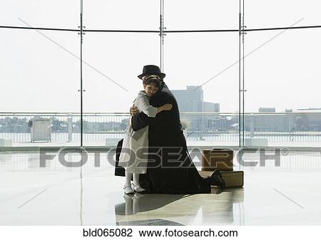 Stock Image - Hispanic father hugging daughter in airport. Fotosearch