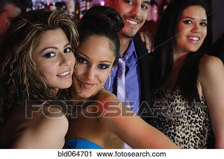 Stock Image - Hispanic friends enjoying nightclub. Fotosearch