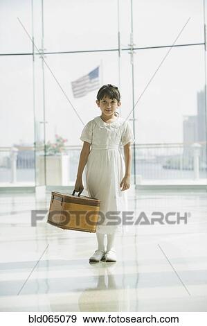 Stock Photo - Hispanic girl with suitcase waiting in airport. Fotosearch