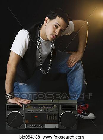 Hispanic man crouching near boom box View Large Photo Image Stock Photo - Hispanic man crouching near boom box. Fotosearch