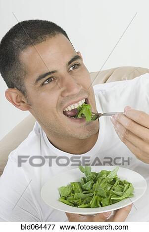Stock Photo - Hispanic man eating salad. Fotosearch