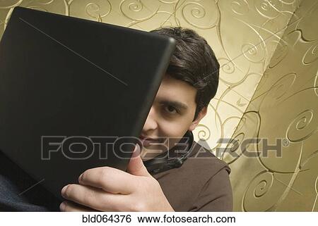 Hispanic man hiding behind laptop View Large Photo Image Stock Photograph - Hispanic man hiding behind laptop. Fotosearch