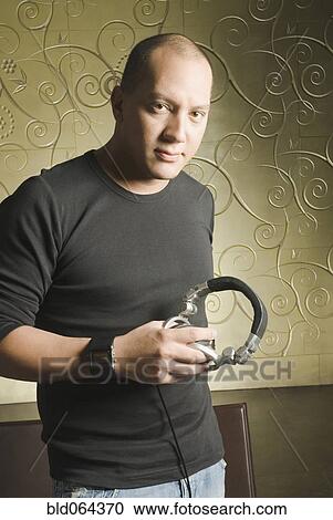 Stock Image - Hispanic man holding headphones. Fotosearch