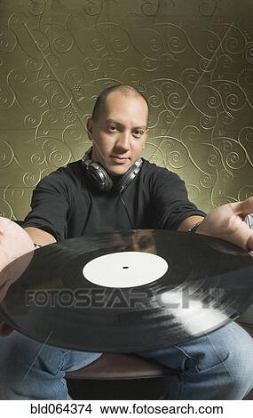 Picture - Hispanic man holding vinyl record. Fotosearch