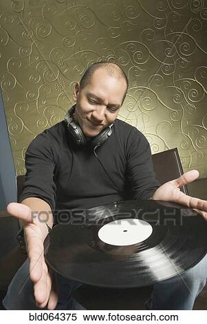 Stock Photography - Hispanic man holding vinyl record. Fotosearch