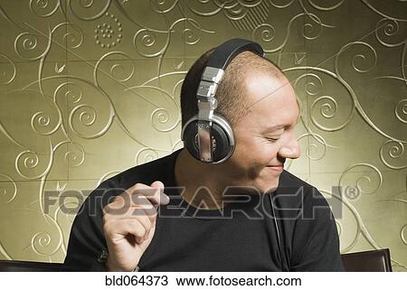 Stock Image - Hispanic man listening to headphones. Fotosearch