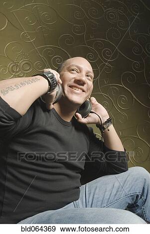 Stock Photo - Hispanic man listening to headphones. Fotosearch