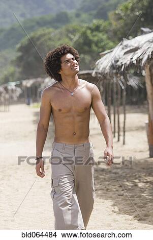Picture - Hispanic man walking on beach. Fotosearch