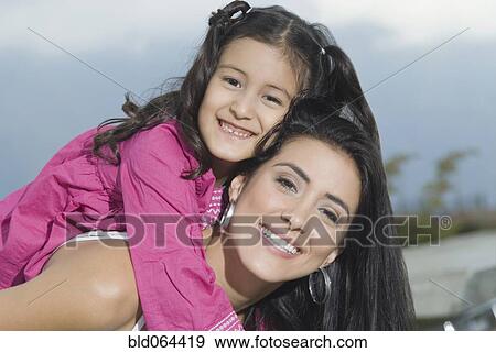 Stock Photo - Hispanic mother giving daughter piggyback ride. Fotosearch