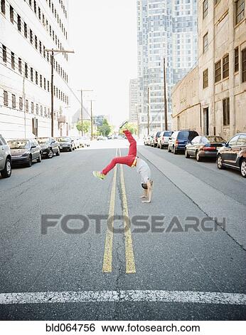 Stock Photograph - Hispanic teenage boy doing back flip in urban street. Fotosearch