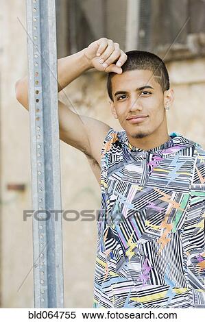 Stock Photography - Hispanic teenage boy leaning against metal post. Fotosearch