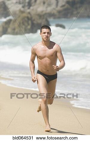 Stock Image - Hispanic teenager running on beach. Fotosearch