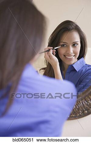 Stock Image - Hispanic woman applying eyeliner. Fotosearch