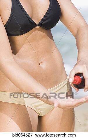 Hispanic woman applying sunscreen at beach View Large Photo Image Stock Photo - Hispanic woman applying sunscreen at beach. Fotosearch