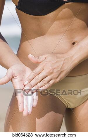 Hispanic woman applying sunscreen at beach View Large Photo Image Stock Photo - Hispanic woman applying sunscreen at beach. Fotosearch
