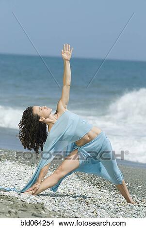 Picture - Hispanic woman doing yoga at beach. Fotosearch