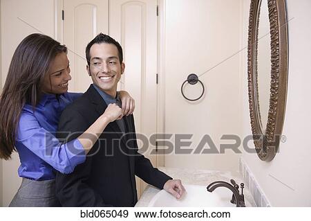 Stock Photo - Hispanic woman helping husband with necktie. Fotosearch