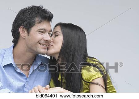 Stock Image - Hispanic woman kissing boyfriend. Fotosearch