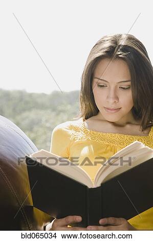 Picture - Hispanic woman reading book. Fotosearch