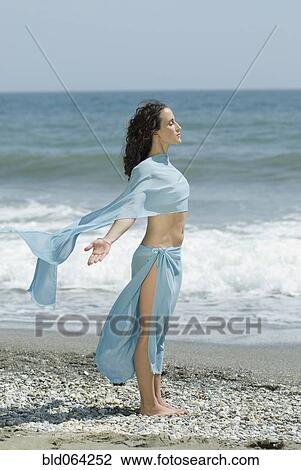 Stock Image - Hispanic woman relaxing at beach. Fotosearch
