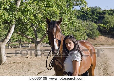 Stock Photo - Middle Eastern woman standing with horse. Fotosearch