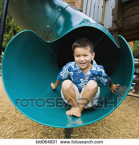 Stock Image - Mixed race boy sliding in playground. Fotosearch