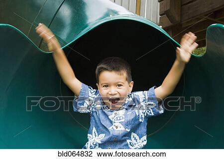 Stock Image - Mixed race boy sliding in playground. Fotosearch