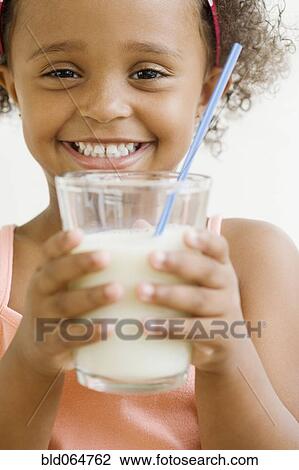 Stock Image - Mixed race girl holding glass of milk. Fotosearch