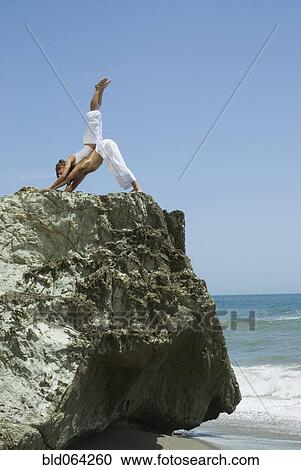Stock Image - Multi-ethnic couple doing yoga at beach. Fotosearch