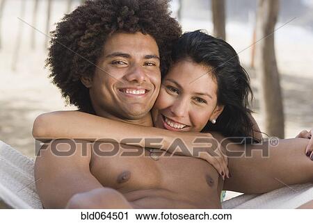 Stock Image - Multi-ethnic couple laying in hammock. Fotosearch