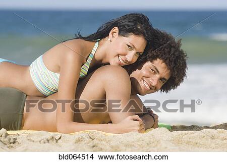 Multi-ethnic couple laying on beach View Large Photo Image Picture - Multi-ethnic couple laying on beach. Fotosearch