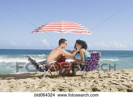 Multi-ethnic couple relaxing at beach View Large Photo Image Picture - Multi-ethnic couple relaxing at beach. Fotosearch