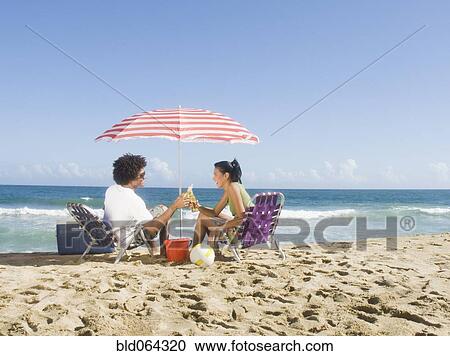 Multi-ethnic couple relaxing at beach View Large Photo Image Stock Image - Multi-ethnic couple relaxing at beach. Fotosearch