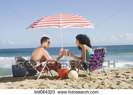 Multi-ethnic couple relaxing at beach View Large Photo Image Stock Image - Multi-ethnic couple relaxing at beach. Fotosearch