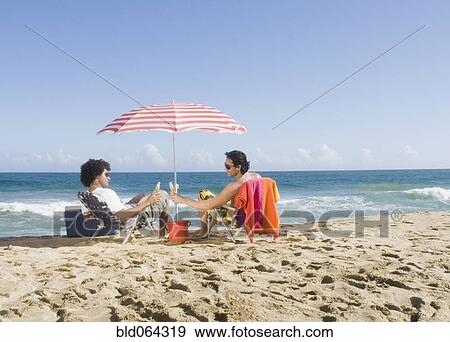 Multi-ethnic couple relaxing at beach View Large Photo Image Stock Photo - Multi-ethnic couple relaxing at beach. Fotosearch
