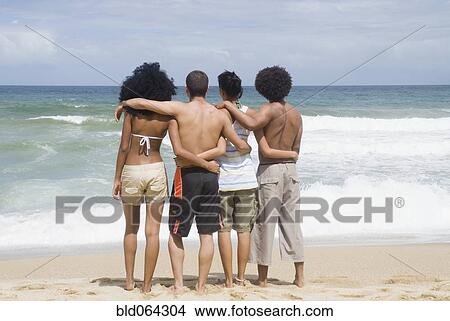 Picture - Multi-ethnic friends hugging at beach. Fotosearch