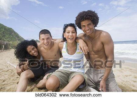Stock Image - Multi-ethnic friends hugging at beach. Fotosearch