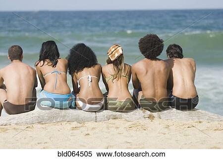 Stock Photography - Multi-ethnic friends relaxing on beach. Fotosearch