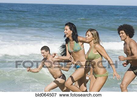 Multi-ethnic friends running on beach View Large Photo Image Stock Photo - Multi-ethnic friends running on beach. Fotosearch