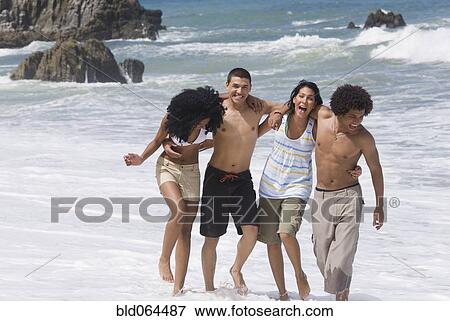 Multi-ethnic friends walking on beach View Large Photo Image Stock Photo - Multi-ethnic friends walking on beach. Fotosearch