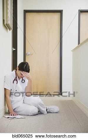 Stock Photography - Nurse sitting on floor feeling ill. Fotosearch