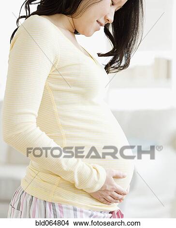 Picture - Pregnant Asian woman caressing stomach. Fotosearch