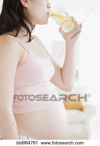 Stock Image - Pregnant Asian woman drinking water. Fotosearch