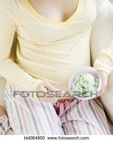 Stock Image - Pregnant Asian woman eating ice cream. Fotosearch