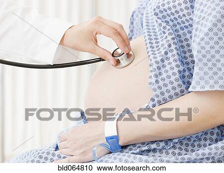 Stock Image - Pregnant Asian woman having checkup in doctor’s office. Fotosearch